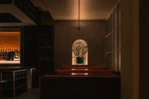 Cozy restaurant interior with dim lighting, red tables and chairs, and stone walls