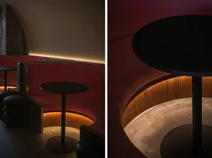 Modern restaurant interior with red walls, wooden elements, and a dining area with tables and chairs
