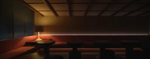 Inviting restaurant interior with a long bench seating area, multiple tables, chairs, and a couch, creating a cozy atmosphere for dining and socializing