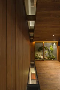 Warm and inviting indoor space with wooden walls and floors, featuring potted plants and a vase, creating a cozy ambiance