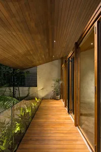 Open living area with wooden floors and walls, glass doors to a patio, potted plants, and a warm and cozy atmosphere