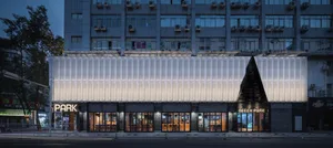 Modern building with a white facade featuring a unique pattern and numerous windows, set in a city environment
