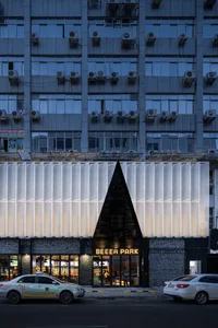 A modern building with a large white triangle on its side, featuring white and grey elements, windows, and a clean minimalist appearance