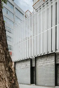 A modern building with a large glass wall and metal-clad exterior, featuring a minimalist and contemporary design with abundant natural light