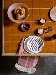 A kitchen dining area with a wooden table set up with food, cups, and apples, creating a warm and inviting atmosphere