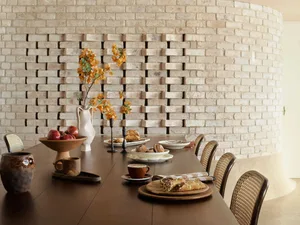 Dining area with a wooden table, chairs, plates, cups, and vases, set in a restaurant or upscale home