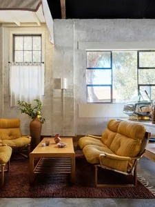 Cozy modern living room with yellow couches and chairs, a rug, and a coffee table, featuring a welcoming atmosphere and natural lighting