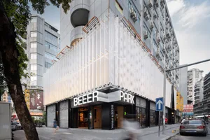 一間熱鬧的白色立面餐廳，設有戶外座位區，以及醒目的「Beer Park」招牌，背景為模糊的人群與周遭環境