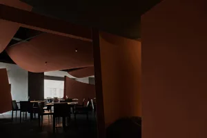 A warm and inviting dining space with a large table, red walls, and wine glasses, perfect for socializing and dining