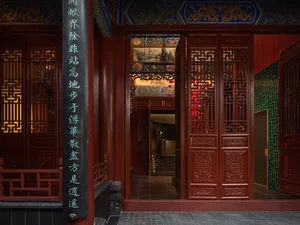 Ornate red building with Chinese lettering and intricate carvings, featuring a large archway entrance and comfortable seating areas