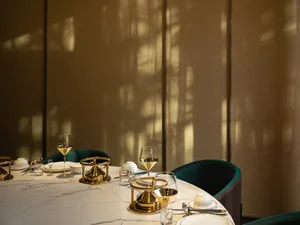 Elegant dining area with a round table, wine glasses, cups, and bowls, set for a formal dinner in a refined atmosphere