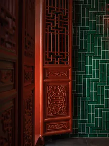 Asian-inspired interior design with red wooden doors featuring intricate carvings and Chinese characters, set against a backdrop of green tiled walls in a dimly lit space