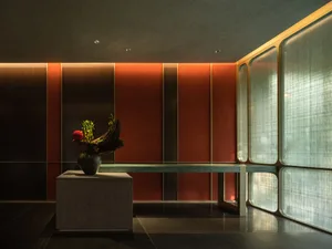 A well-lit interior space with a stone table, a large vase with flowers, and a warm atmosphere