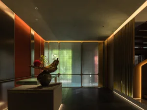 Empty room with a vase on a table in front of a window, dimly lit with a minimalist aesthetic