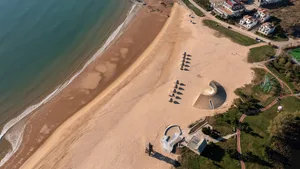 A beach scene with scattered umbrellas, sand, and water, evoking a relaxing atmosphere