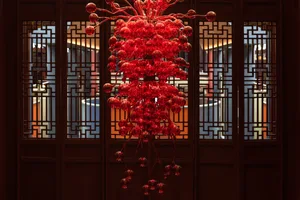 A dimly lit room with an ornate red chandelier and dark background, creating a sophisticated atmosphere