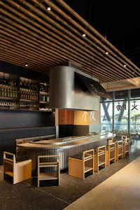 Modern Asian restaurant bar with a countertop, chairs, and bottles of various sizes displayed, creating a functional and stylish atmosphere