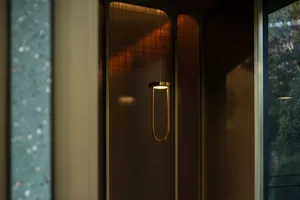 A warm and inviting entryway with a wooden door, a gold light fixture, and brown tones
