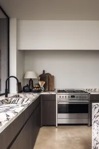 A modern kitchen with a marble countertop, stove, sink, and various kitchen items