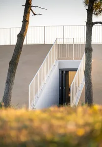A modern building with a metal staircase leading to a doorway, with a person standing near the bottom of the stairs