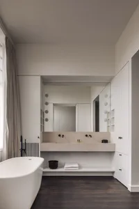 A modern bathroom with a white bathtub and two sinks, a mirror above the sink area, and a clean and simple design