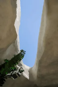 A large rock formation with a central cave or tunnel, surrounded by rocks and possibly vegetation, creating a unique atmosphere