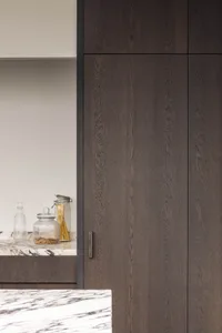 Warm kitchen space with wooden cabinets and countertops, featuring bottles, a bowl, and a spoon