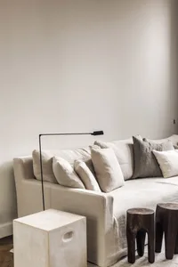 A living room with a couch, two chairs, and wooden stools on a white carpet, creating a comfortable and inviting atmosphere