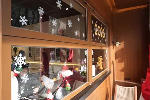 零售店門面櫥窗展示冬季服飾，玻璃上點綴雪花，背景是購物環境中的人群