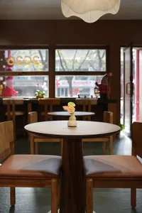 A cozy restaurant interior with wooden tables and chairs, a vase on one table, and an inviting atmosphere