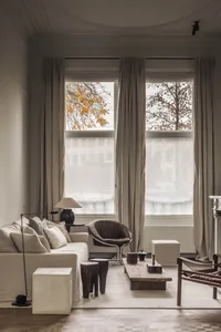 Cozy living area with a couch, chair, and coffee table, surrounded by decorative items and natural light from two windows