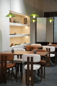 Modern restaurant interior with wooden tables and chairs, white walls, and brown wood accents, creating a warm and inviting atmosphere