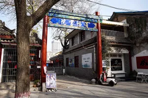 熱鬧的亞洲城市街角，一座紅色建築擁有大型拱門入口與招牌，周圍環繞著人群與車輛