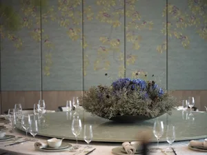 Elegant dining area with a round table, flowers, wine glasses, and fine china