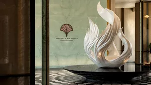 A white bird sculpture sits on a pedestal in front of a wall, showcasing intricate marble details in a sophisticated indoor setting