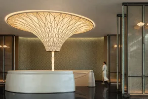 A modern dining space with a metal chandelier, a dining table, and two people, suggesting a stylish and contemporary interior design