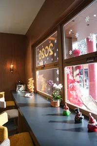 A well-lit dining area with a wooden table surrounded by chairs, featuring potted plants and various decorative items