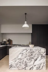 Elegant kitchen with marble countertops, a large island, two sinks, and a refrigerator, featuring a modern and stylish design