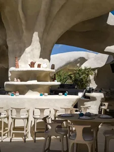 A well-designed restaurant with white theme, decorative elements, dining tables, chairs, and mixed textures on the walls
