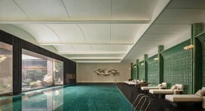 A relaxing pool area with a blue tiled pool, surrounded by chairs and couches, creating a serene atmosphere
