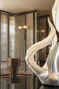 A modern interior space with a large marble sculpture, glass wall, and two lights, creating a contemporary atmosphere