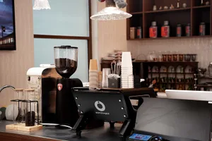 A casual coffee shop interior with cups, bottles, and a teddy bear, featuring a comfortable atmosphere and inviting decor