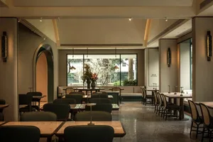 Modern restaurant interior with tables, chairs, potted plants, and inviting ambiance