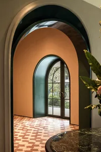 A well-lit interior space with a yellow-painted wall, a glass door, and an archway leading to another room