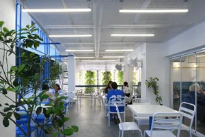 casual dining space with wooden tables and chairs, people sitting and standing around, well-lit