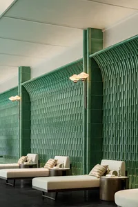 A modern interior space with green walls and three white chairs arranged in a row, creating a fresh and inviting atmosphere