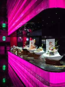 高雅餐廳內部，設有大型餐桌、粉色牆面，以及各式食物與座椅