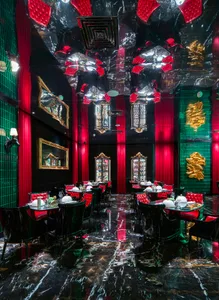 Modern restaurant interior with red walls, black accents, and tables and chairs, featuring wine glasses and a bar
