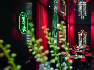 Warm and inviting Asian restaurant interior with red walls, green neon lights, chairs, tables, and a bar area with a countertop and decorative items
