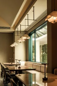 Empty restaurant interior with natural light, dining tables, chairs, and hanging lights